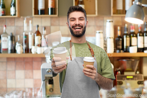 Image of happy smiling barman in apron with takeaway coffee