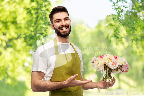 Image of smiling male gardener with bunch of peony flowers