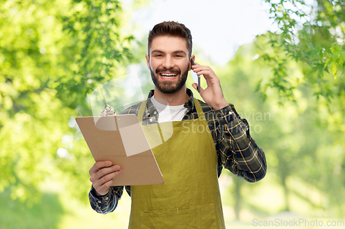 Image of male gardener with clipboard calling on smartphone