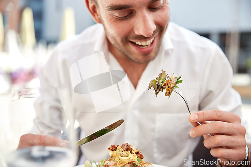 Image of close up of happy man eating food at restaurant