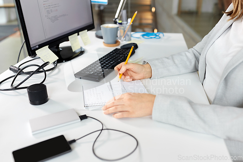 Image of businesswoman with notebook and computer at office