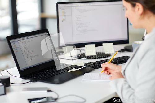 Image of businesswoman with notebook and laptop at office