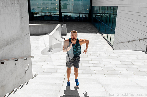 Image of young man in headphones running upstairs outdoors