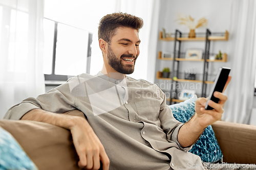 Image of happy smiling young man with smartphone at home