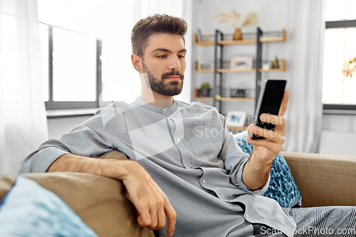 Image of young man with smartphone at home