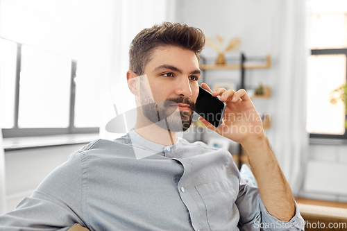 Image of man calling on smartphone at home