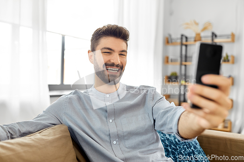 Image of man with smartphone having video call at home