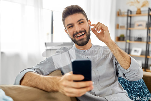 Image of man in earphones listening to music on smartphone