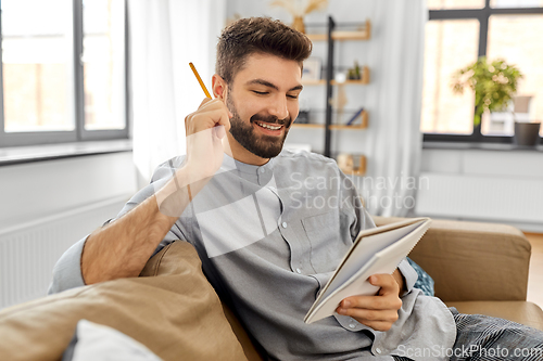 Image of smiling man with to notebook and pencil at home