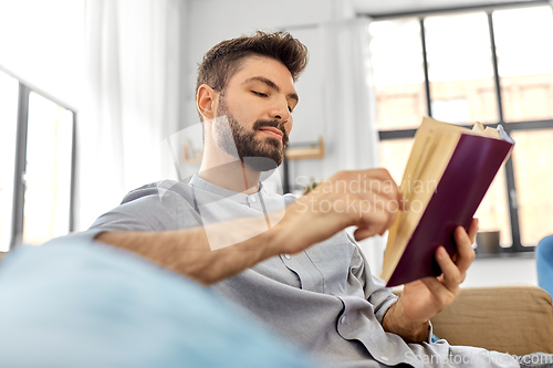 Image of man reading book at home