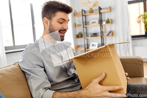 Image of happy smiling man with open parcel box at home