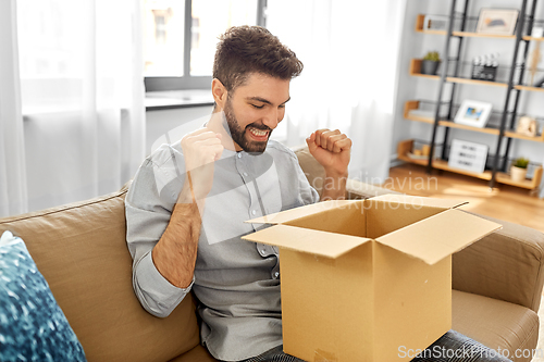 Image of happy smiling man with open parcel box at home