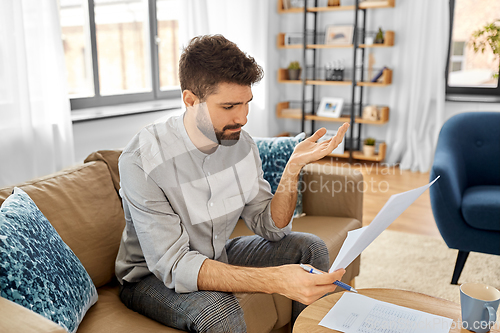 Image of stressed man with bills at home