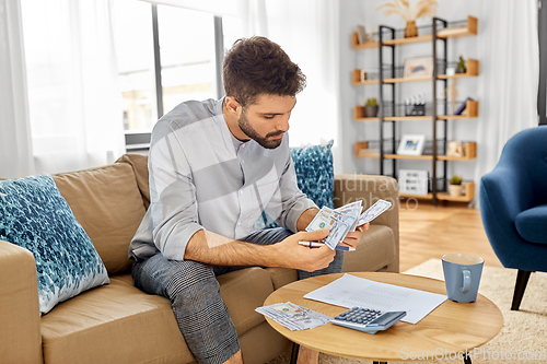 Image of man with money and calculator filling papers