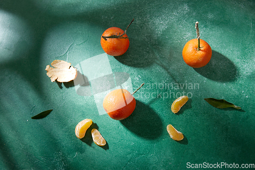 Image of still life with mandarins on green background