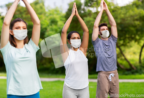 Image of group of people doing yoga at summer park