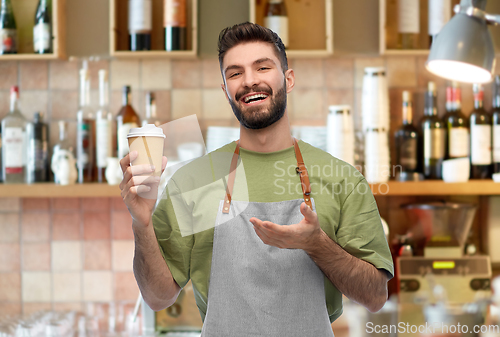 Image of happy smiling barman in apron with takeaway coffee