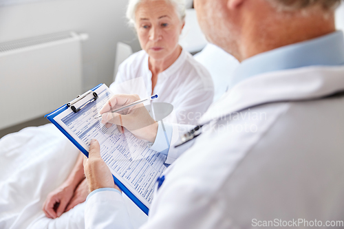 Image of senior woman and doctor with clipboard at hospital