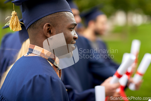 Image of graduate students in mortar boards with diplomas