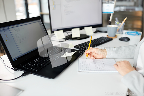 Image of businesswoman with notebook and laptop at office