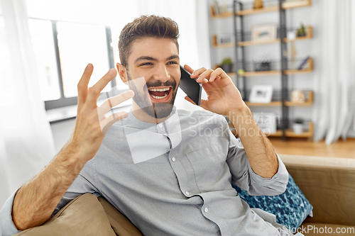 Image of happy man calling on smartphone at home