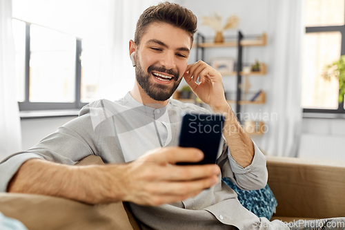 Image of man in earphones listening to music on smartphone