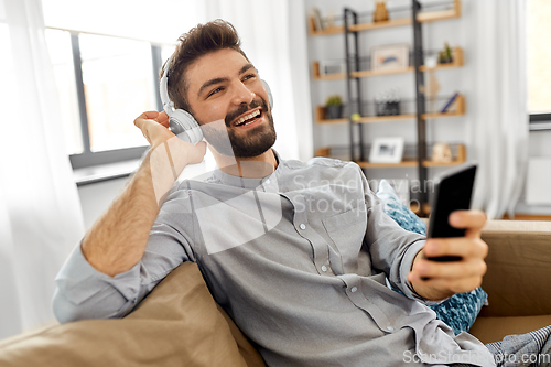 Image of man in headphones listening to music on smartphone