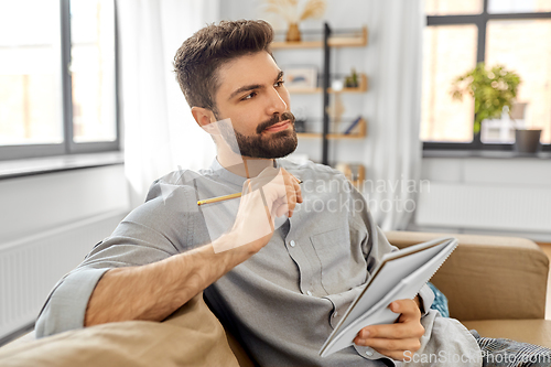 Image of man writing to notebook and thinking at home