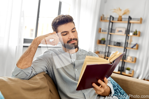 Image of man reading book at home