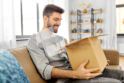 Image of happy smiling man opening parcel box at home