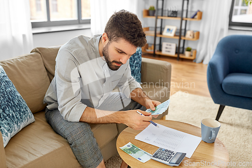 Image of man with money and calculator filling papers