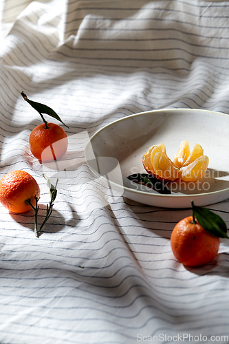 Image of still life with mandarins on plate over drapery