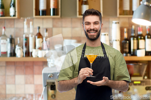 Image of barman in apron with glass of cocktail at bar