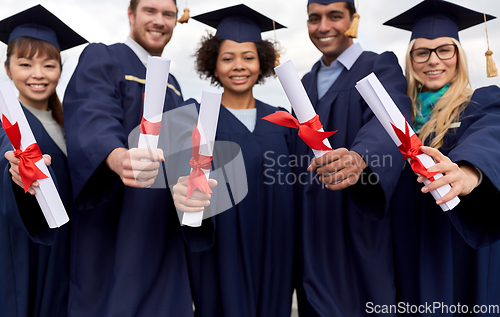 Image of graduate students in mortar boards with diplomas