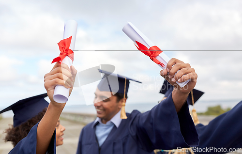 Image of graduate students in mortar boards with diplomas