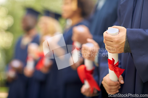 Image of graduate students in mortar boards with diplomas