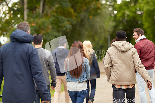 Image of happy friends walking along autumn park