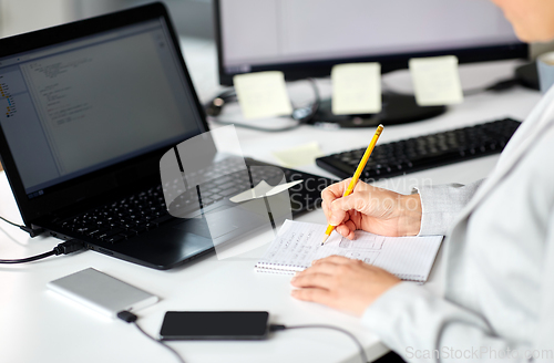 Image of businesswoman with notebook and laptop at office