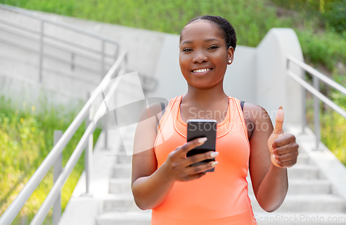 Image of smiling sporty african woman using smartphone