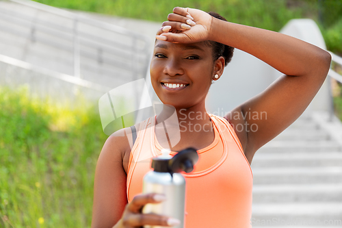 Image of tired african american woman with bottle of water