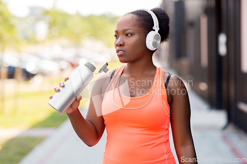 Image of african american woman drinking water after sports