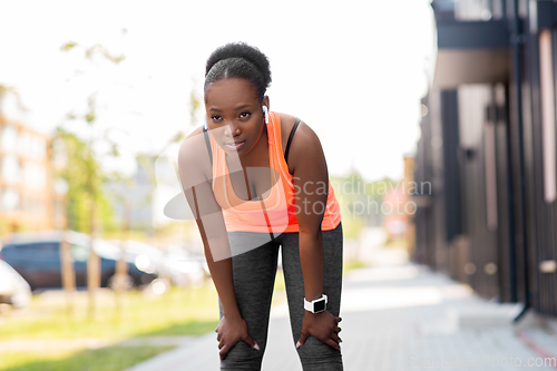 Image of tired african american woman with earphones