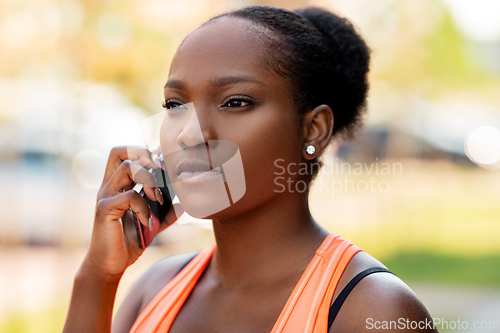 Image of sporty african woman calling on smartphone in city