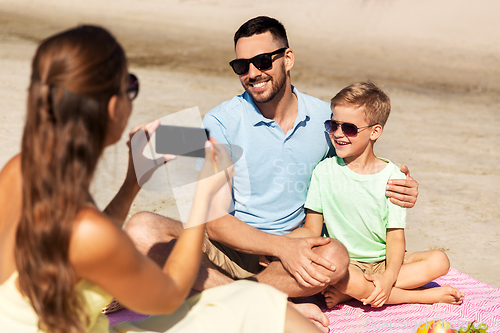 Image of family with smartphone photographing on beach