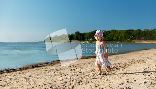 Image of happy baby girl running on summer beach