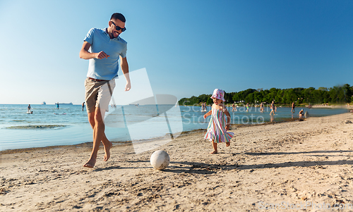 Image of happy father and daughter playing ball on beach