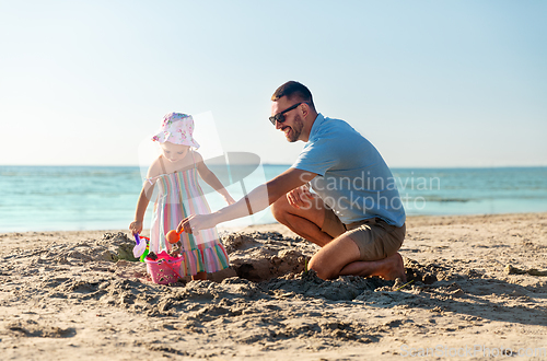 Image of father and daughter playing with toys on beach