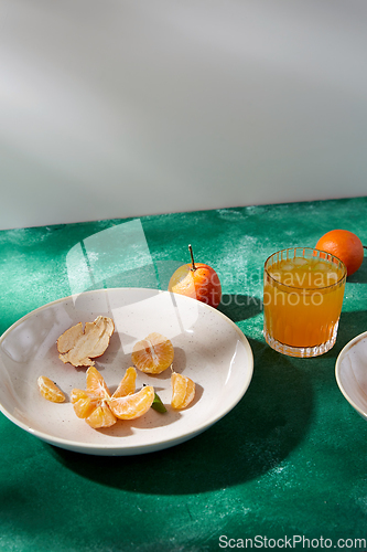 Image of peeled mandarins on plate and glass of juice