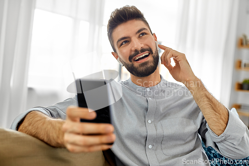 Image of man in earphones listening to music on smartphone