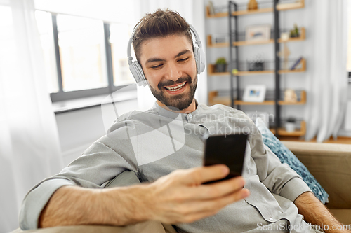 Image of man in headphones listening to music on smartphone
